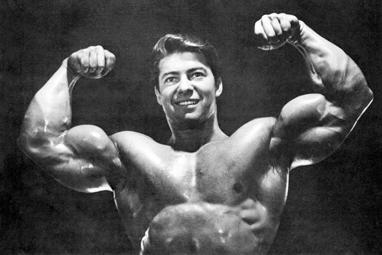 fisiculturista Larry Scott fazendo uma pose de duplo bíceps