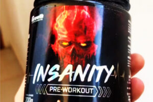 segurando um pote do pré-treino Insanity da Growth Supplements