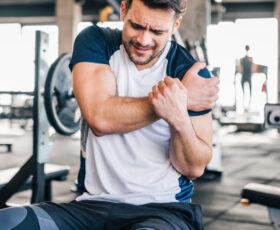 praticante de musculação sentindo dor no ombro na academia